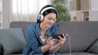 Rahat kadın evde bir kanepede oturan akıllı telefon video izleme