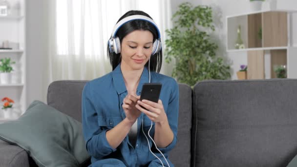 愉快的妇女放松听音乐坐在舒适的沙发上在家里 — 图库视频影像