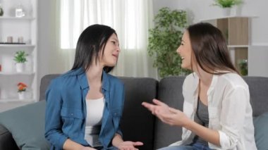 Mutlu arkadaş konuşurken ve tebrik ve iyi haber evde bir kanepede oturan kutluyor sarılma