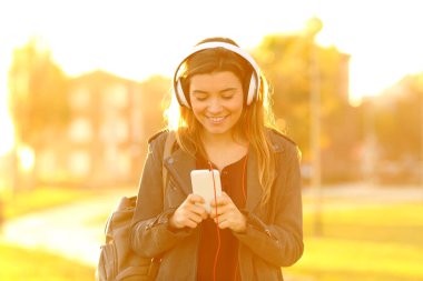 Günbatımı müzik akıllı telefon dinleme, mutlu bir genç kız portresi önden görünüm