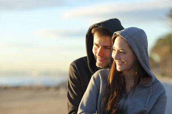 愉快的夫妇的青少年考虑在海滩上的日落坐姿 — 图库照片