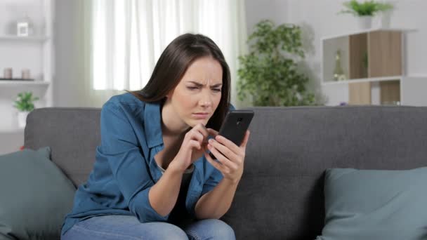 妇女遭受眼睛疲劳使用智能手机坐在沙发上在家里 — 图库视频影像