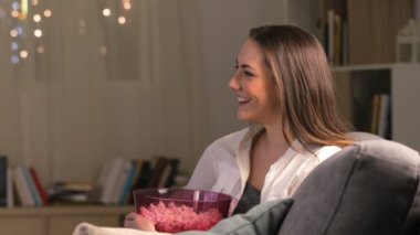 Yan görünüm portre hayran bir kadının evde bir kanepede oturan gece tv izlerken