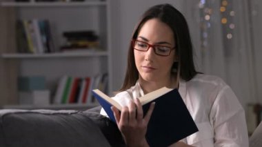 Ciddi bir kadın gece bir kanepede oturan bir kitap okuma önden görünümü