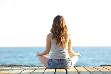 Yoga egzersizleri sahilde pratik bir genç kız portresi arkadan görünüm