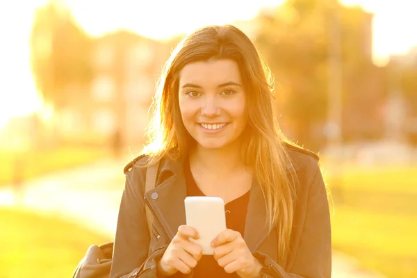 Widok Przodu Portret Szczęśliwy Nastolatki Trzymając Telefon Patrząc Kamery Zachodzie — Zdjęcie stockowe