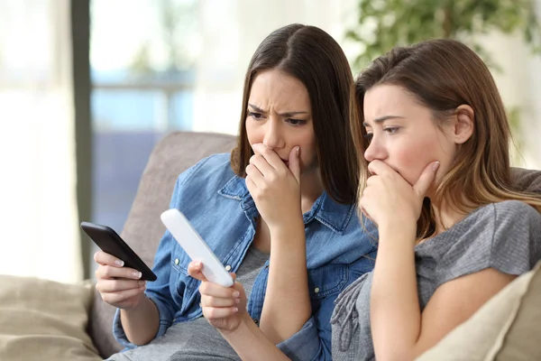 Duas Mulheres Preocupadas Verificando Conteúdo Telefones Inteligentes Sentadas Sofá Sala — Fotografia de Stock