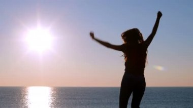 Arkadan görünüşü sahilde atlama gündoğumu kutluyor mutlu bir kadın