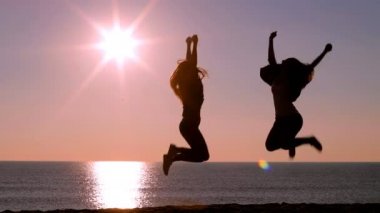Tam vücut iki heyecan arkadaş kumsalda güneş doğarken yükselterek silah atlama