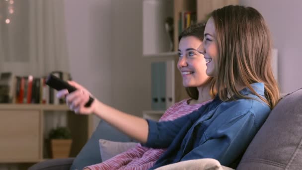 两个快乐的朋友坐在家里的沙发上看电视 — 图库视频影像