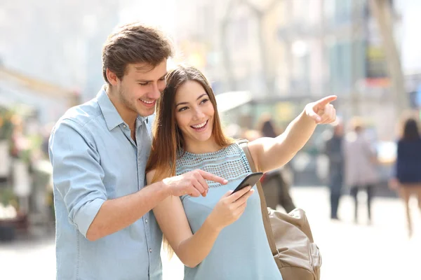 快乐的朋友或夫妻在街上用智能手机查看位置 — 图库照片