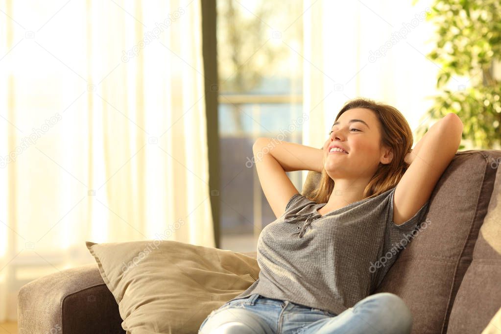 Happy woman resting comfortably sitting on a couch in the living room at home