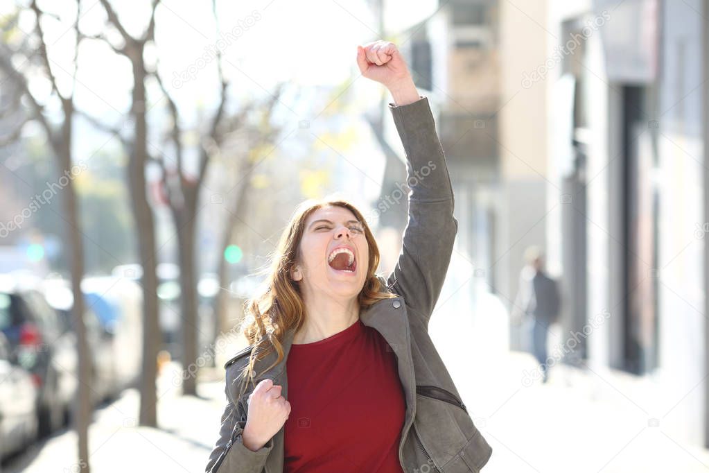 Front view portrait of an excited teen celebrating good news in the street