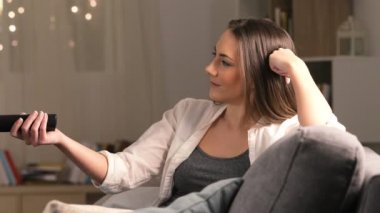 Gece evde bir kanepede oturup tv izlerken mutlu bir kadın yan görünüm