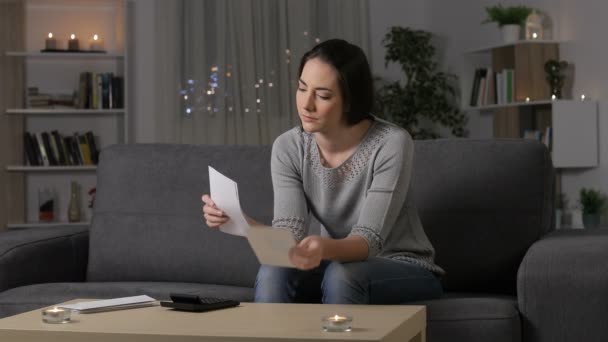 夜自宅のソファに座って手紙を読んで混乱している女性 — ストック動画