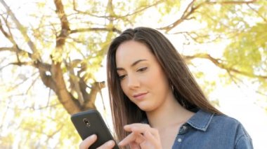 Akıllı telefon ayakta bir parkta kullanan ciddi bir kadın portresi