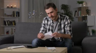 Şaşkın adam gece evde bir kanepede oturan bir mektup okuma