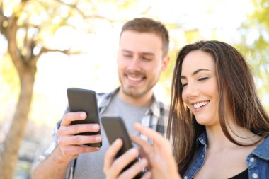 İki mutlu arkadaş parkın dışında akıllı telefonlarını kullanıyor.