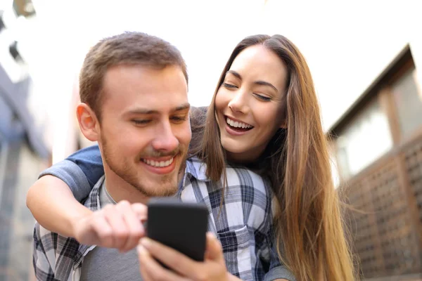 Front View Happy Couple Piggybacking Checking Smart Phone Street — Stock Photo, Image