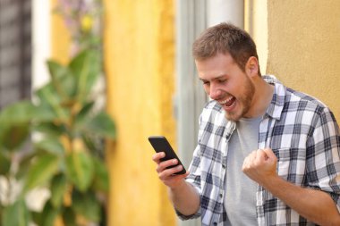 Heyecanlı akıllı telefon iyi haber kutlama kontrol sokakta adam 