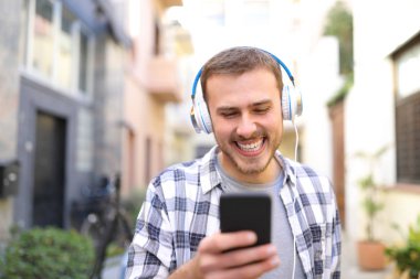 Sokakta yürürken akıllı telefon kullanarak müzik dinlemek mutlu bir adam portresi Önden Görünüm