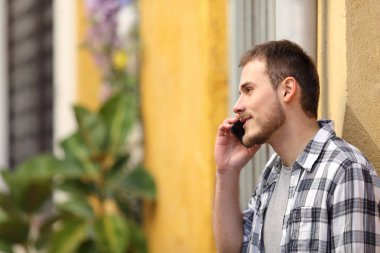 Ciddi bir adam renkli bir sokakta telefonla konuşuyor.