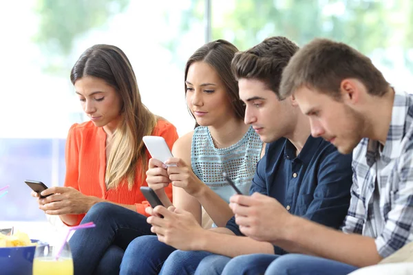 Grupo Amigos Sérios Usando Seus Telefones Inteligentes Sentados Sofá Sala — Fotografia de Stock