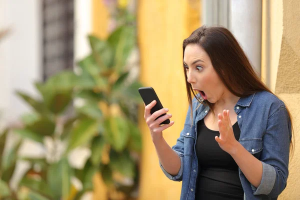 路上でスマートフォンでオンラインニュースをチェックする驚きの女性 — ストック写真