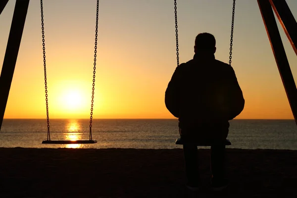 Rückseite Hintergrundbeleuchtung Silhouette Eines Mannes Der Allein Auf Schaukel Sitzt — Stockfoto