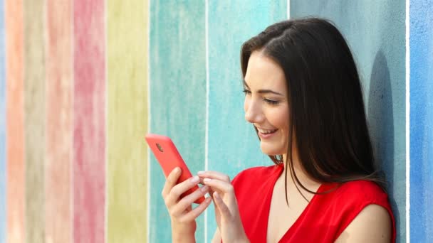 Überraschte Frau Überprüft Smartphone Inhalte Lehnt Einer Bunten Wand Auf — Stockvideo