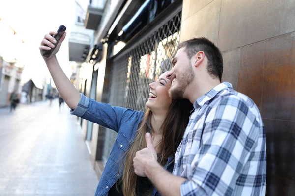 Пара, делающая селфи со смартфоном на улице — стоковое фото