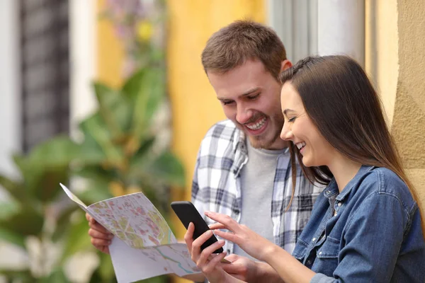 Coppia felice di turisti controllare telefono e mappa — Foto Stock