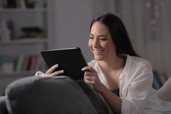 Mujer feliz viendo los medios de comunicación en la tableta en la noche — Foto de Stock