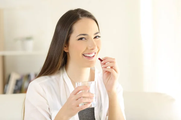 Mulher feliz tomando cápsula analgésica em casa — Fotografia de Stock