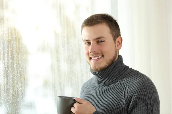 Nöjd hyresgäst tittar kameran bredvid ett fönster hemma — Stockfoto