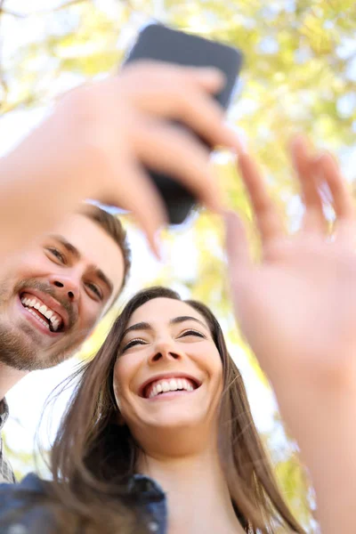 幸せなカップルが公園で一緒にスマート フォンを使用して — ストック写真