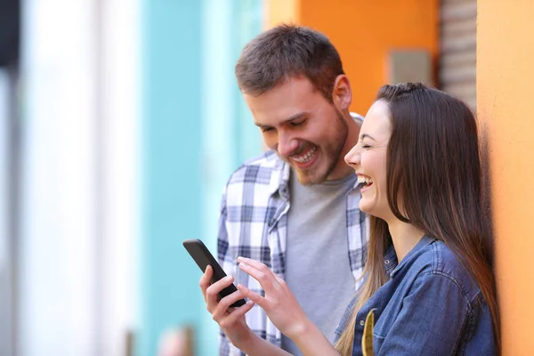 Pareja feliz riendo comprobando el teléfono inteligente —  Fotos de Stock