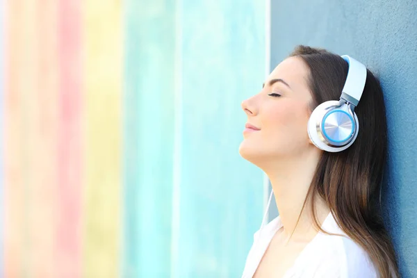 Menina relaxada ouvindo música em uma parede colorida — Fotografia de Stock