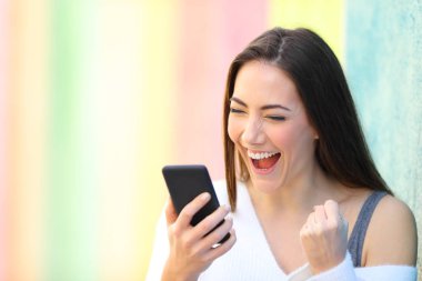 Heyecanlı kız telefonu renkli bir sokakta iyi haber okuma