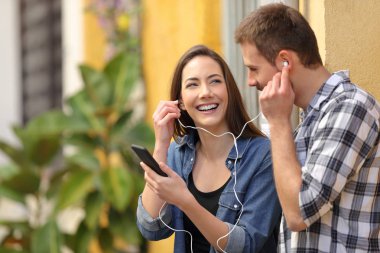 Mutlu çift renkli bir sokakta müzik paylaşımı