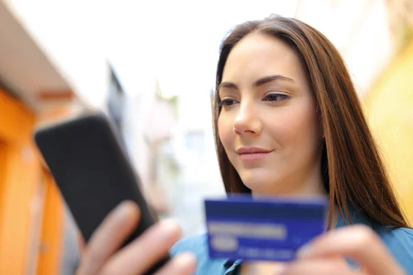 Femme sérieuse payant avec carte de crédit et téléphone portable à l'extérieur — Photo