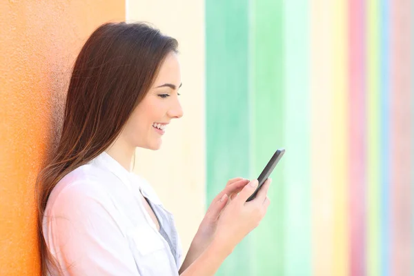 Vista lateral de una chica usando el teléfono en una calle colorida — Foto de Stock