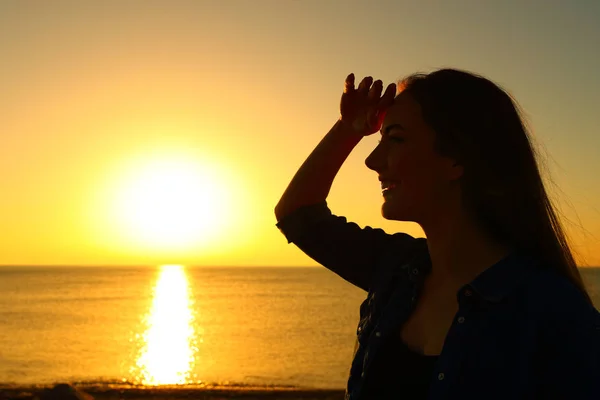 Siluett av en kvinna som scouting vid soluppgången på stranden — Stockfoto