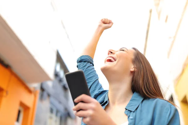 Mulher excitada segurando telefone inteligente celebra o sucesso — Fotografia de Stock