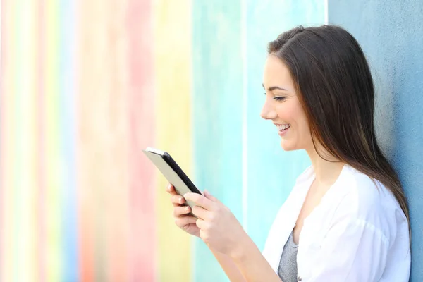 Menina feliz ler conteúdo em um tablet em uma rua colorida — Fotografia de Stock