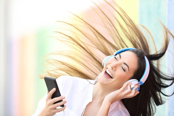 Счастливая женщина слушает музыку, танцующую на разноцветной улице — стоковое фото