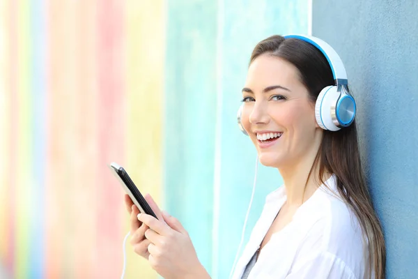 Счастливая женщина смотрит на вас, слушая музыку из планшета — стоковое фото
