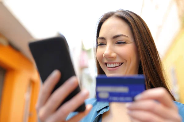 Mujer feliz paga en línea con tarjeta de crédito en la calle — Foto de Stock