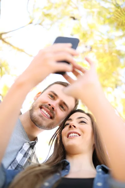 Pareja feliz está usando un teléfono inteligente en un parque — Foto de Stock