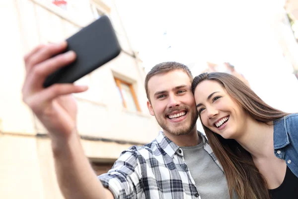 Happy couple taking selfies with smartphone in the street — Stock Photo, Image